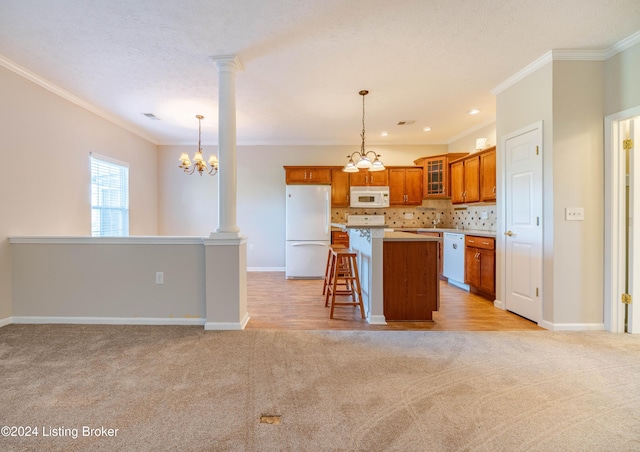 kitchen with crown molding, pendant lighting, a chandelier, white appliances, and a kitchen island