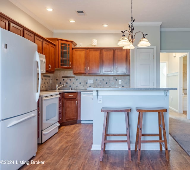 kitchen featuring dark hardwood / wood-style floors, crown molding, a chandelier, white appliances, and decorative light fixtures