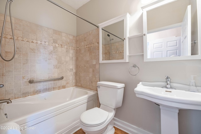 full bathroom with sink, tiled shower / bath, and toilet