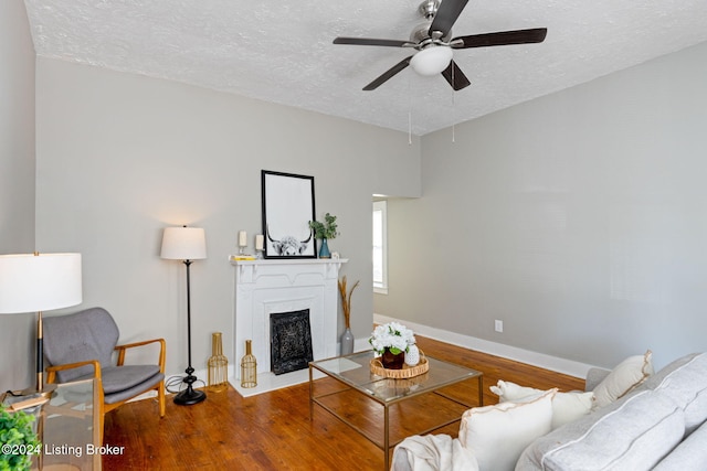 living room with ceiling fan, wood-type flooring, and a textured ceiling