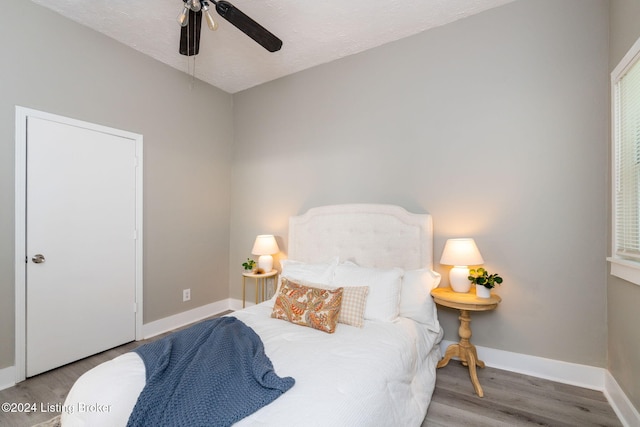 bedroom with ceiling fan, light hardwood / wood-style floors, and a textured ceiling