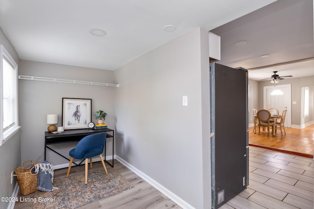 home office with ceiling fan and light hardwood / wood-style flooring