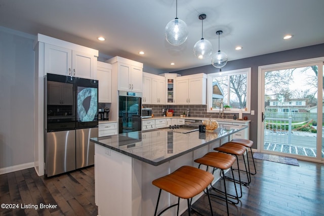 kitchen with black appliances, a kitchen island, dark hardwood / wood-style flooring, and stone counters