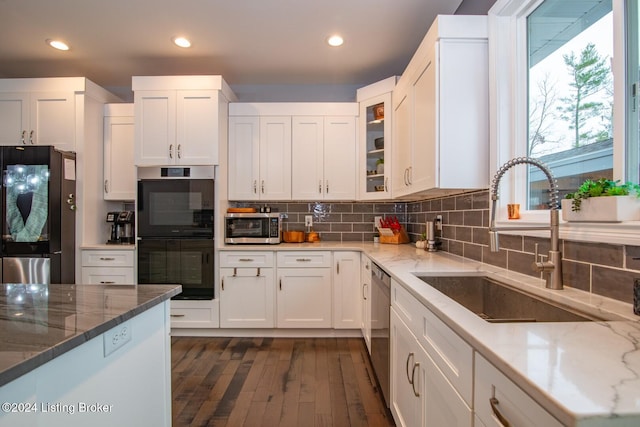 kitchen featuring white cabinets, sink, light stone counters, and black appliances