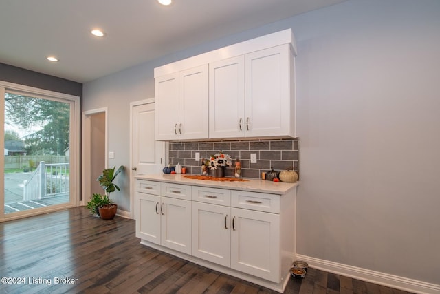 bar with dark hardwood / wood-style flooring, white cabinetry, and tasteful backsplash