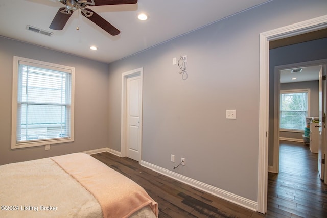 bedroom featuring ceiling fan, dark hardwood / wood-style flooring, and multiple windows