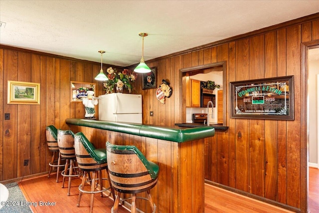 bar featuring wood walls, white fridge, and light wood-type flooring