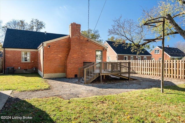 back of property featuring central AC, a wooden deck, and a lawn