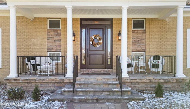 snow covered property entrance featuring covered porch