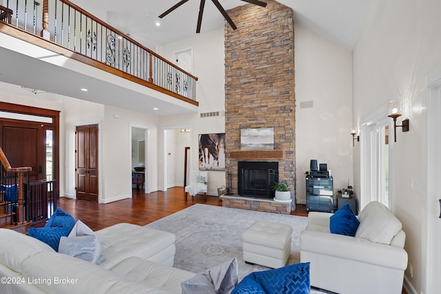 living room with a stone fireplace, wood-type flooring, and high vaulted ceiling