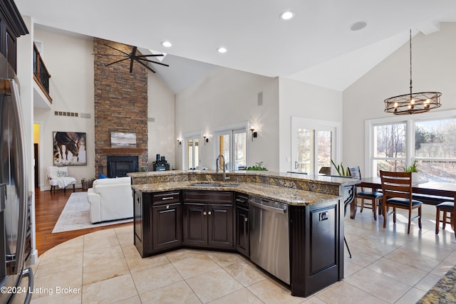 kitchen with sink, an island with sink, high vaulted ceiling, and appliances with stainless steel finishes