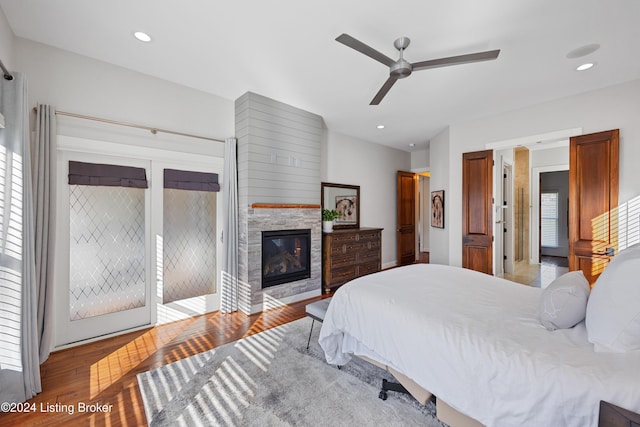 bedroom featuring multiple windows, ceiling fan, a stone fireplace, and light hardwood / wood-style floors