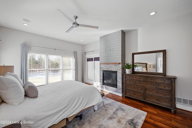 bedroom featuring dark hardwood / wood-style floors, ceiling fan, and a fireplace