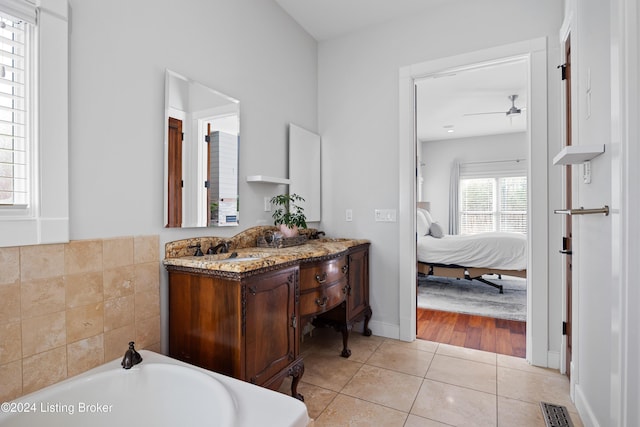 bathroom featuring tile patterned flooring, ceiling fan, a tub to relax in, and vanity