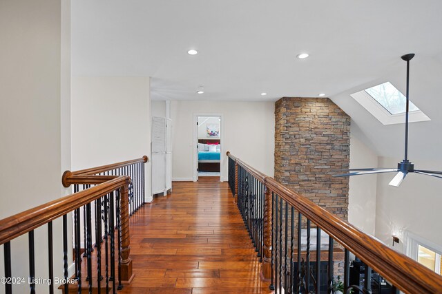 hall with lofted ceiling with skylight and dark wood-type flooring