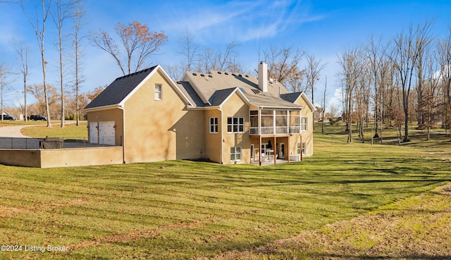 back of house with a sunroom, a garage, and a yard