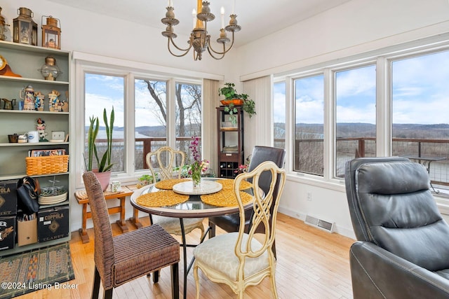 dining space with light hardwood / wood-style floors and a notable chandelier