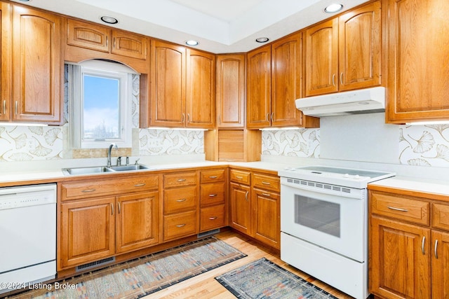 kitchen with white appliances, backsplash, light hardwood / wood-style flooring, and sink