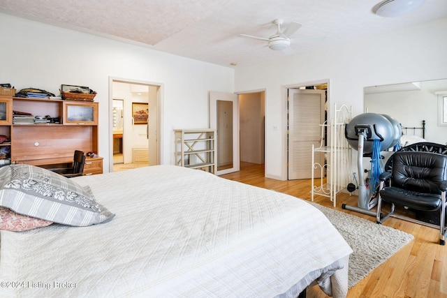 bedroom featuring a textured ceiling, light wood-type flooring, ensuite bath, and ceiling fan