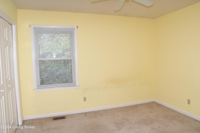 empty room featuring ceiling fan and light colored carpet