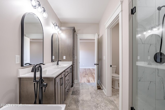 full bath with walk in shower, baseboards, toilet, double vanity, and a sink