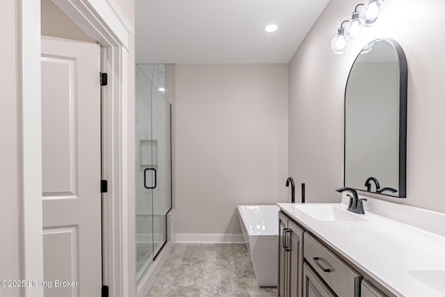 full bath featuring baseboards, double vanity, a bathtub, a stall shower, and a sink