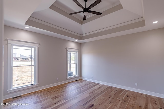 unfurnished room featuring visible vents, baseboards, light wood-type flooring, and a tray ceiling