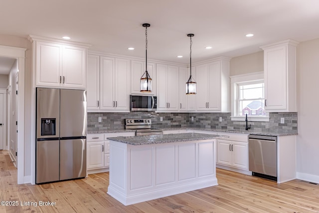 kitchen with a sink, appliances with stainless steel finishes, white cabinets, and light wood finished floors