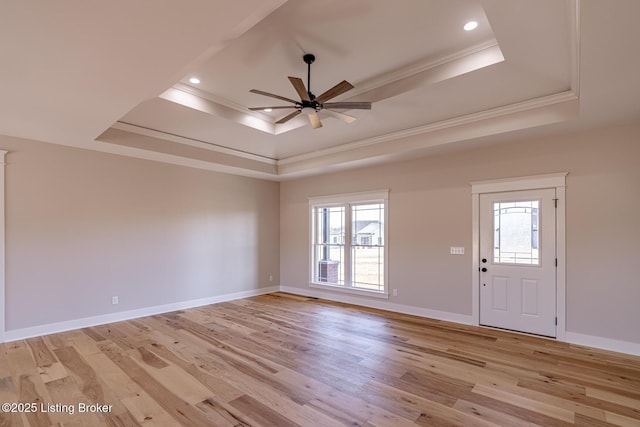 foyer featuring a wealth of natural light, a raised ceiling, and ornamental molding