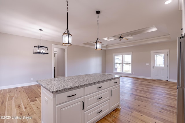 kitchen featuring light wood-style flooring, baseboards, and a tray ceiling