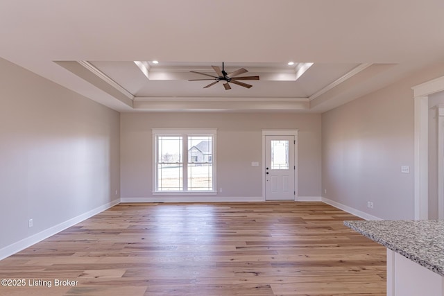 foyer entrance featuring light wood-style flooring, baseboards, and a tray ceiling