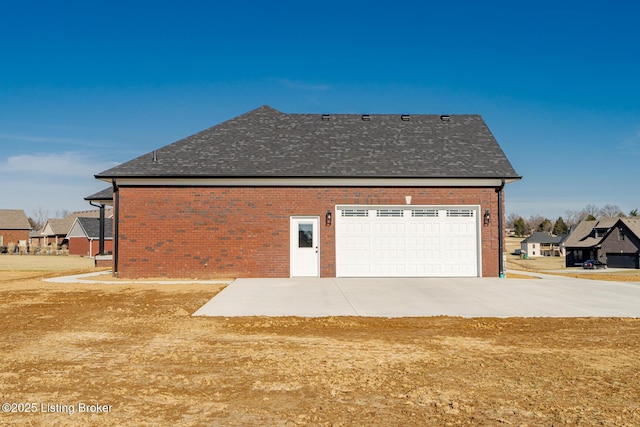 view of home's exterior with a residential view, brick siding, roof with shingles, and driveway