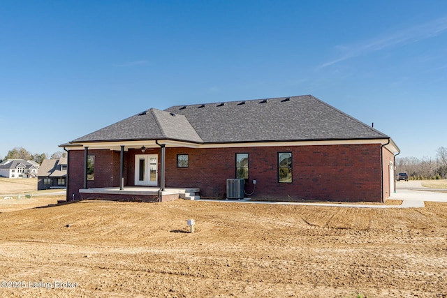 back of property featuring brick siding, cooling unit, a ceiling fan, and roof with shingles