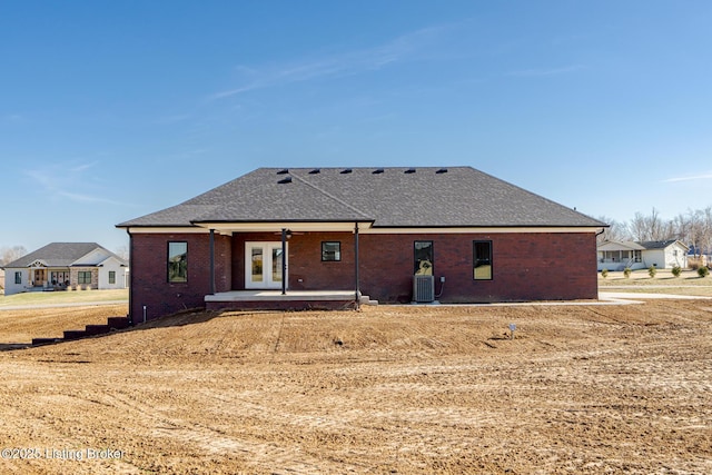 rear view of property with french doors, brick siding, a shingled roof, and a patio area