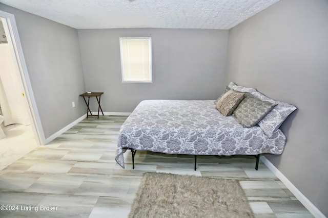 bedroom with light hardwood / wood-style floors and a textured ceiling