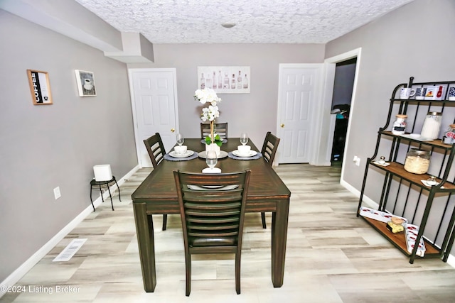 dining space featuring light hardwood / wood-style floors and a textured ceiling