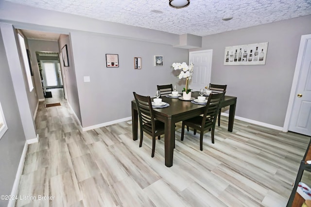 dining room with a textured ceiling and light hardwood / wood-style floors