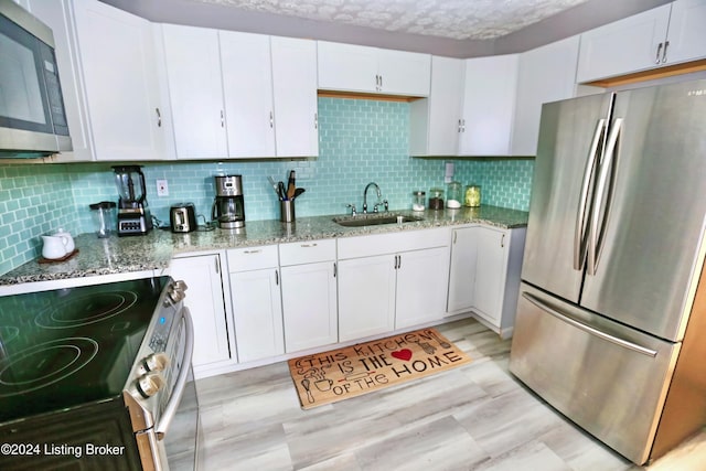 kitchen with light stone counters, white cabinetry, sink, and appliances with stainless steel finishes