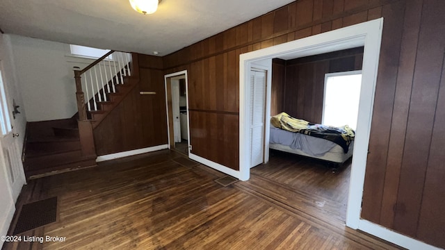 entryway with dark hardwood / wood-style floors and wooden walls