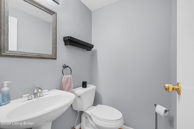 bathroom with a textured ceiling, toilet, and sink