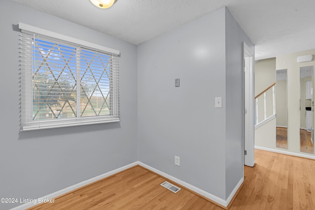 empty room with a textured ceiling and light wood-type flooring