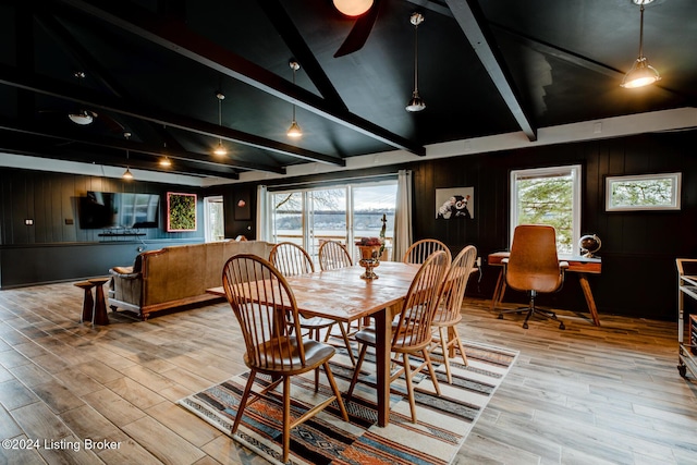 dining area featuring vaulted ceiling with beams, light wood-type flooring, ceiling fan, and wooden walls