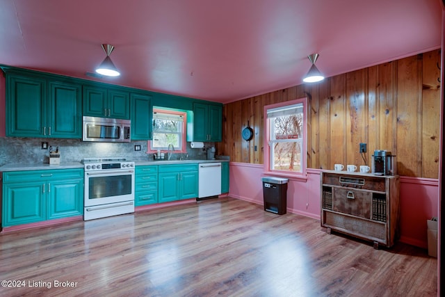 kitchen featuring sink, light hardwood / wood-style flooring, backsplash, wood walls, and white appliances