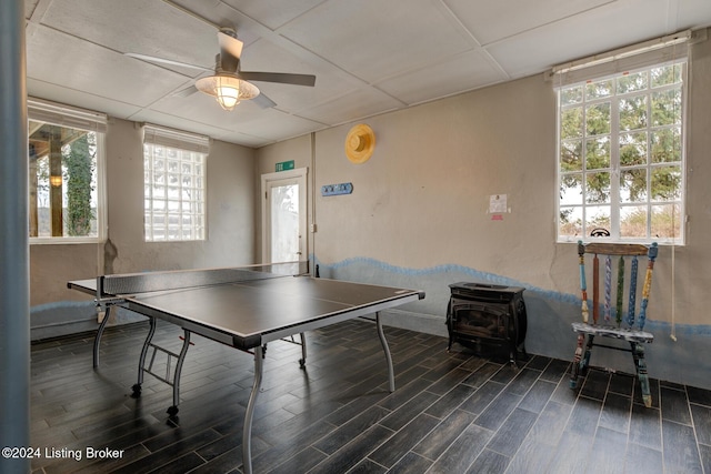 rec room featuring a wood stove, ceiling fan, and dark hardwood / wood-style flooring