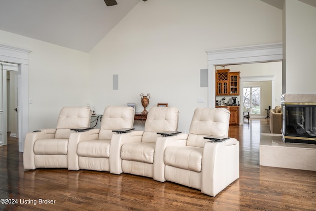 cinema room with high vaulted ceiling, bar, and dark wood-type flooring