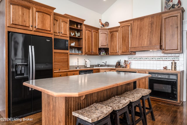 kitchen featuring a center island, vaulted ceiling, a breakfast bar area, and black appliances