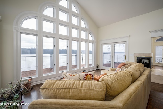 sunroom with plenty of natural light, a water view, a premium fireplace, and lofted ceiling