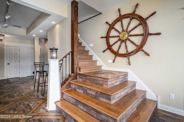 staircase with parquet flooring and a textured ceiling