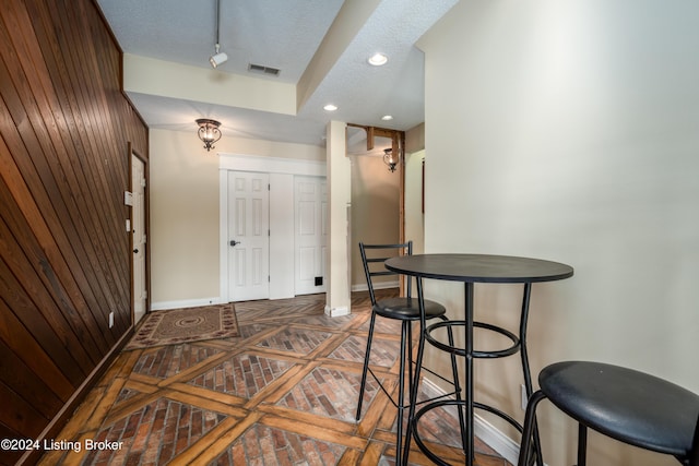 entrance foyer featuring wood walls and a textured ceiling