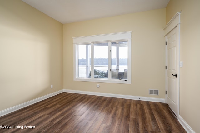 empty room with dark hardwood / wood-style flooring and a water view